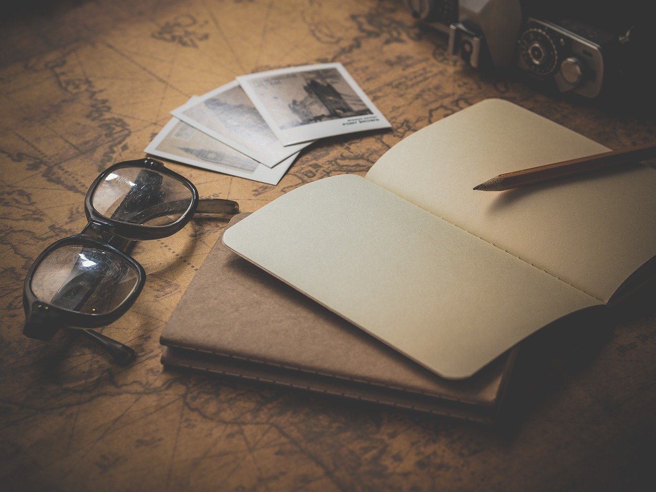 A notebook, glasses and Polaroids on a map