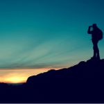 A figure hiking and standing on a mountain