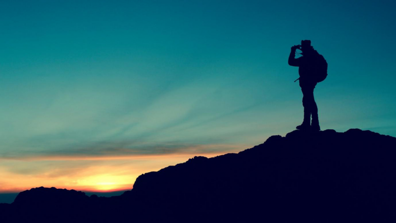 A figure hiking and standing on a mountain