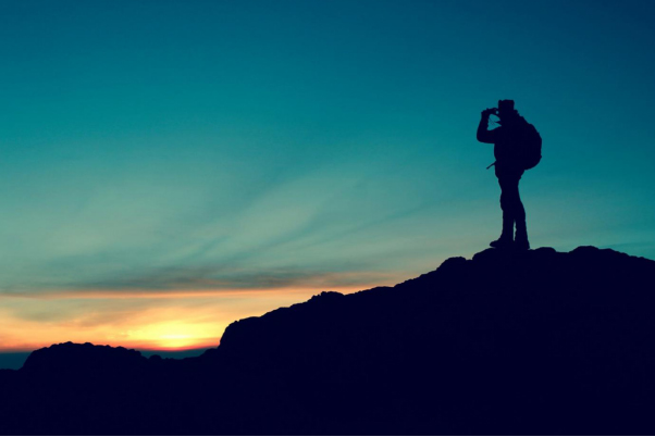 A figure hiking and standing on a mountain